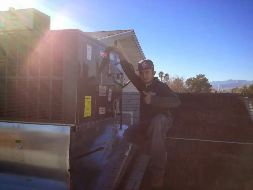 HVAC technician performing Air Duct Repair on a rooftop unit in Glen Burnie